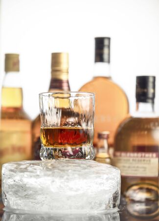 Glass with an alcoholic drink on a large piece of iceの写真素材