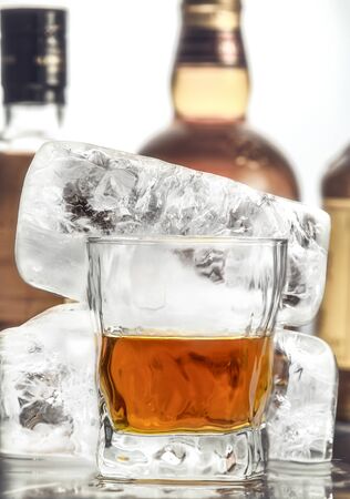 Glass with an alcoholic drink on the background of large pieces of iceの写真素材