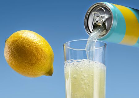 Carbonated drink pours from an aluminum can into a glass