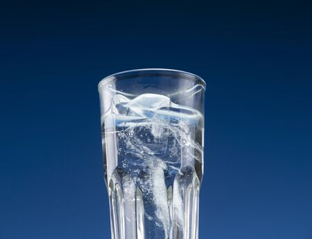 Glass with cold water and ice on a blue backgroundの写真素材