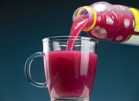 Kissel currant pours from a bottle into a glass mug