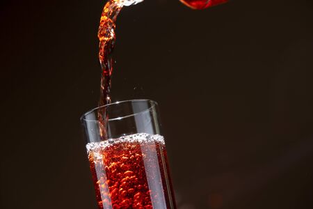 Carbonated cherry drink pouring from a bottle into a glassの写真素材