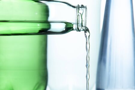 A clear stream of water from the neck of a glass bottle 