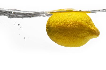 Yellow lemon lit by bright light under waterの写真素材