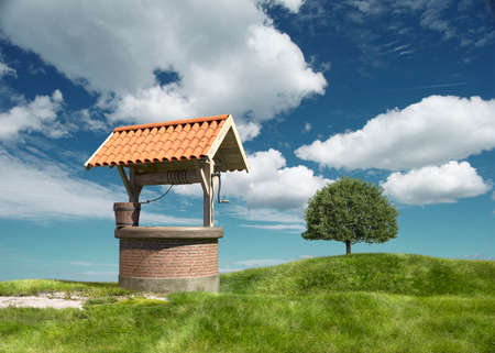 A well under a tiled roof on a grassy hill. 3d renderingの写真素材