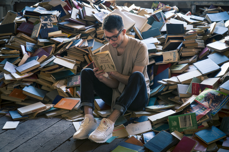 Young man sitting near scattered books