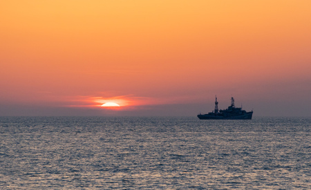 Sunset on the beach of the solar disk dive to half in the sea wavesの写真素材