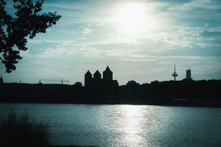 Sunset over Kath. Kirche St. Kunibert Cologne and Rhine river. Silhouette of the left bank of the...