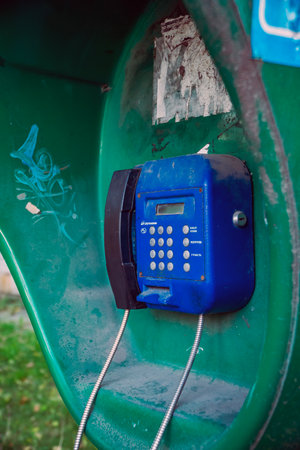 old blue public telephone (payphone). Texture background of a vintage non-working iron street pay phone with buttonsの写真素材