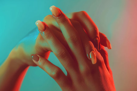 Glamor woman hand with nail polish on her fingernails, pastel warm colorsの素材