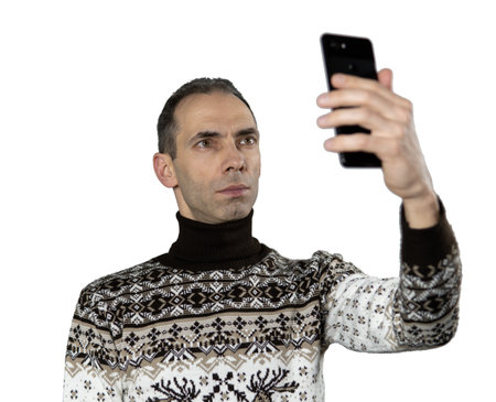 A middle-aged man in a cozy sweater looks at his smartphone, possibly taking a selfie. His expression is thoughtful or slightly surprised. White transparent backgroundの写真素材