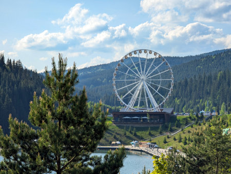 Beautiful picturesque white ferris wheel among coniferous trees in the mountainous areaの写真素材