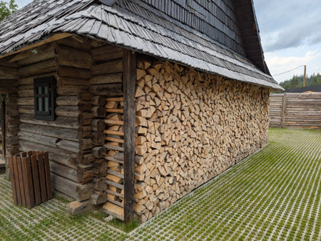 Cross section background of logs of different sizes. Wall of cut brown logs with bark, cracks and...