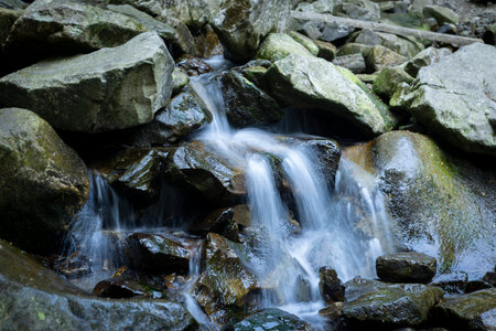 A mountain waterfall among rocks in the Carpathian Mountains in summer.