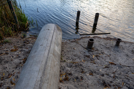 Concrete drainage pipe releasing water into a river surrounded by vegetation.