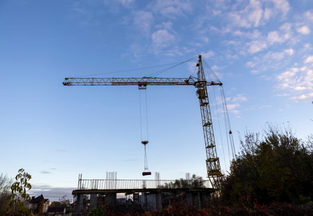 Construction cranes work on creation site against blue sky background. Bottom view of industrial crane. Concept of construction of apartment buildings and renovation of housing. Copy space.の写真素材