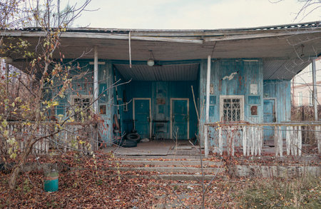 An old abandoned wooden house painted blue stands by the river, once used as a boat station, now weathered and silent.の写真素材