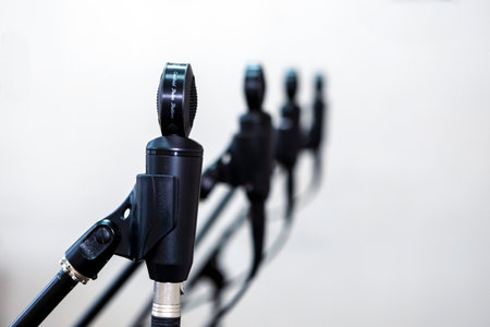 Close-up of microphones in a studio, capturing sound with precision, surrounded by cables and equipment under controlled lighting for recording music or voice.の写真素材