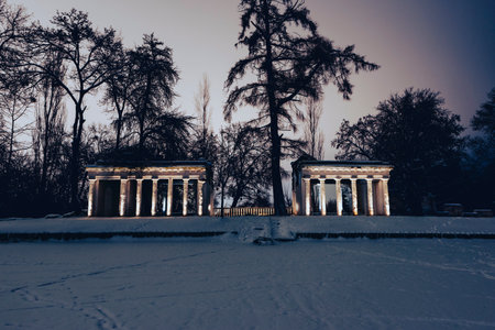 The Ruins architectural complex stands majestic and mysterious, illuminated by warm evening lights in a snowy winter park. The contrast between the weathered stones and fresh white snow creates a fairytale atmosphere.のeditorial素材