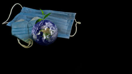 Planet with sprout and medical mask, pandemic health concept, population vaccine, protection of ecology and natureの写真素材