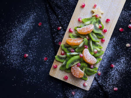 Edible Christmas tree, funny and healthy breakfasts for children, Christmas tree made of kiwi, pomegranate, tangerines, copy spaceの写真素材