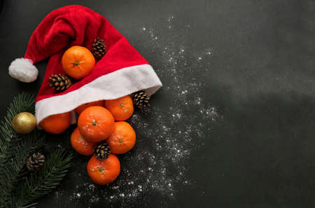 Christmas tangerines in a Santa hat on a black background, Christmas fruits, Merry Christmas, New year and tangerinesの写真素材