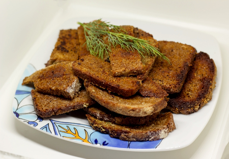plate appetizing pieces of black bread with a sprig of dill fried with garlicの写真素材