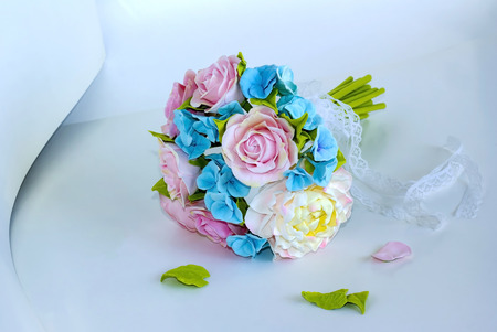 delicate bouquet of pink and blue flowers with a lace ribbon on a light backgroundの写真素材