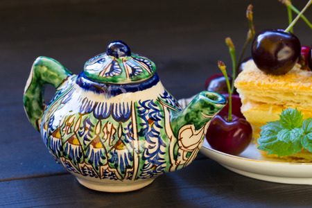 A piece of puff cake with chicken and mint. Dark background. Teapot with Tajik painting.の写真素材
