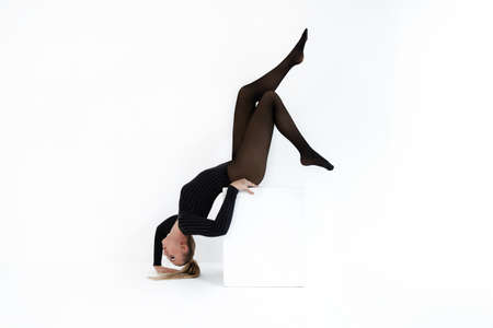 fashion model in black tights on the white background. Acrobatic dancing woman posing. hot blonde girl with long legs in lingerieの写真素材