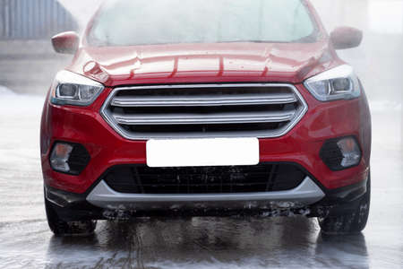 washing car at autowash. Car wash. red machine under the pressure of water at a car wash. car in foam. woman washing carの写真素材