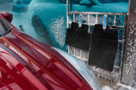 washing car at autowash. Car wash. red machine under the pressure of water at a car wash. car in foam. woman washing carの写真素材