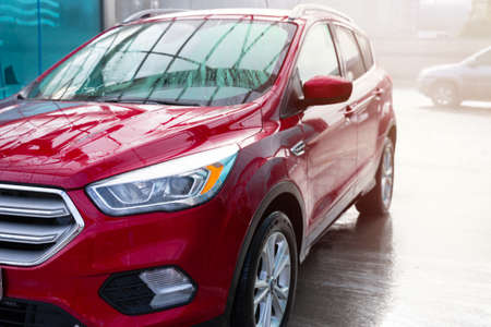 washing car at autowash. Car wash. red machine under the pressure of water at a car wash. car in foam. woman washing carの写真素材