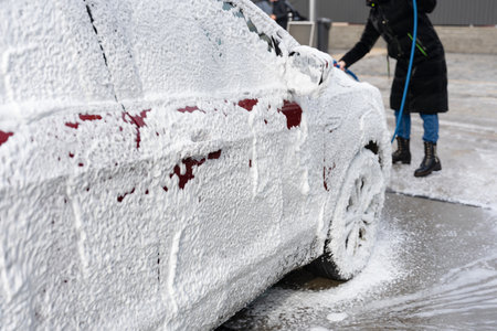 washing car at autowash. Car wash. red machine under the pressure of water at a car wash. Red car in foamの写真素材