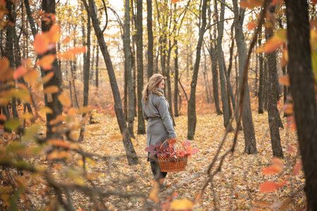 girl in a coat in the autumn forest. redhead woman walking in the park. white boots. Close portrait of beautiful womanの写真素材
