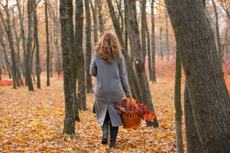 girl in a coat in the autumn forest. redhead woman walking in the park. white boots. Close portrait of beautiful womanの写真素材
