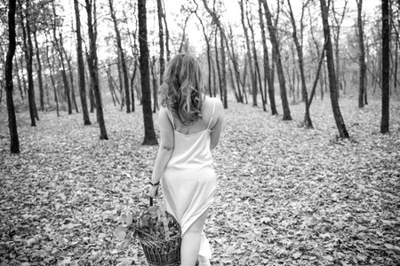 portrait of young red-haired woman in autumn forest. girl in a long white dress with basket. Beautiful women's body in silk nightwear. nymph.wreath of flowersの写真素材