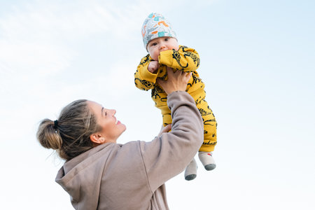 Young beautiful mother plays with her child outdoor. woman hugging her kid against the sea. Happy mother's day. Happy beautiful familyの写真素材