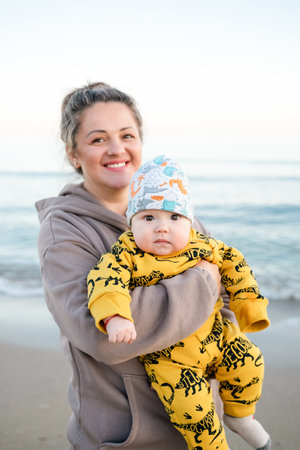 Young beautiful mother plays with her child outdoor. woman hugging her kid against the sea. Happy mother's day. Happy beautiful familyの写真素材