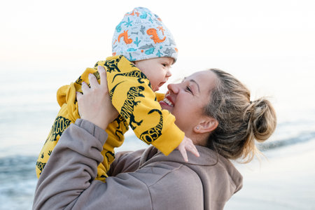 Young beautiful mother plays with her child outdoor. woman hugging her kid against the sea. Happy mother's day. Happy beautiful familyの写真素材