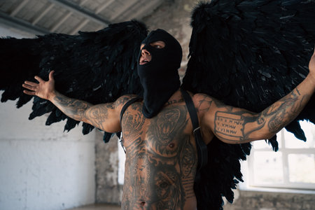 Male angel with black wings. Black angel in a mask. Muscular shirtless man with whip in a mask. Muscular athletic sexy male with naked torso.の写真素材