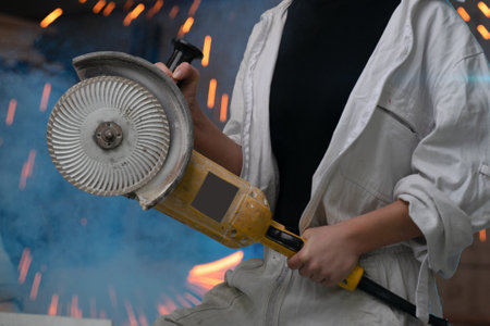 girl working in manufacturing industry job using industrial power tool - Maintenance, production and career concept. worker with angle grinder close-up . feminism. plant, factoryの写真素材