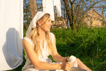 Young woman in white bathrobe sitting on the grass in the parkの写真素材