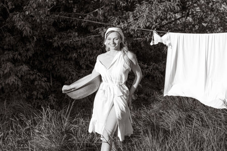 Girl in white dress and hat hanging on clothesline, black and whiteの写真素材