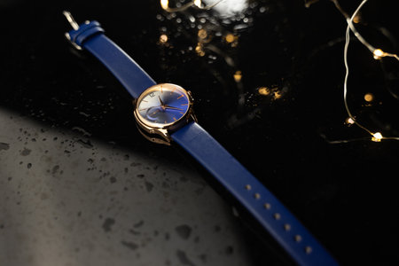 Wristwatch on a black background with garland and water dropsの写真素材