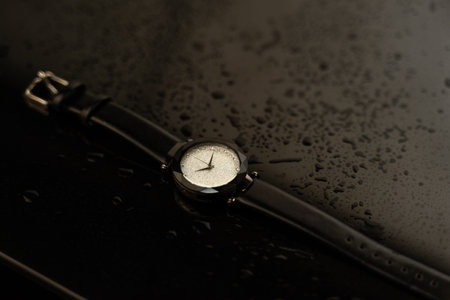 Wrist watch on a black background with water drops, close upの写真素材