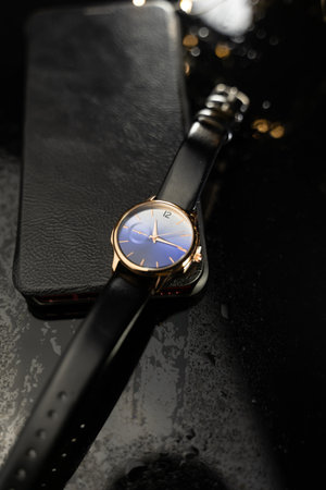 Wrist watch with black dial and gold bracelet on black background.の写真素材