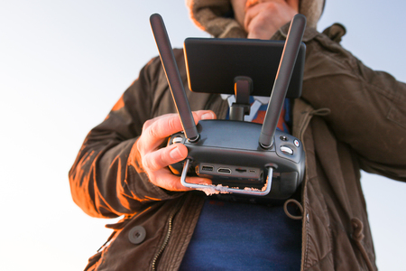 Young man holding the drone remote controller transmitter in his hands in winterの写真素材