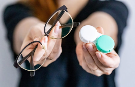 Set for contact lenses and glasses in hands of a woman. The concept of choosing between contact...