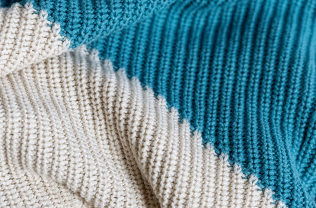 White and turquoise knit wool fabric as a background. Wool knit texture. Knitted fabric surface with...